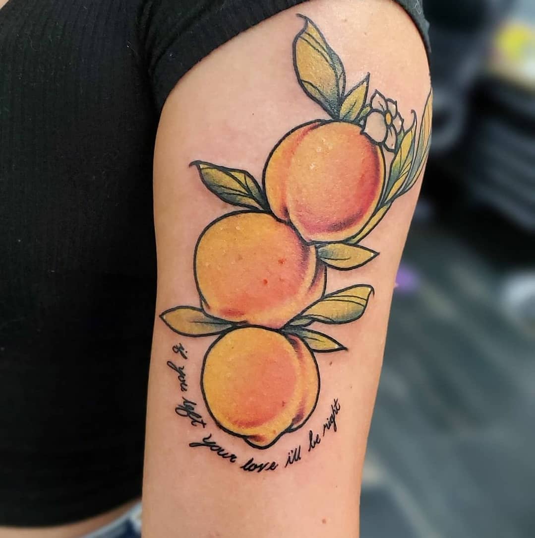 Tattoo of three peaches and a flower on an upper arm with cursive text